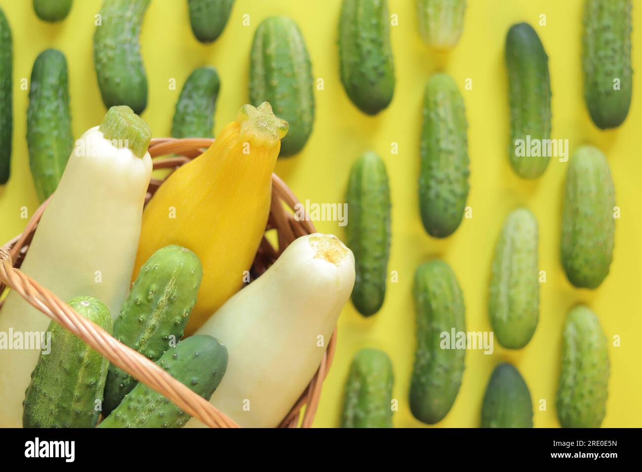 Freshly picked vegetables, zucchini and cucumbers on a yellow background, top view. Selective focus. Basket with vegetables Stock Photo