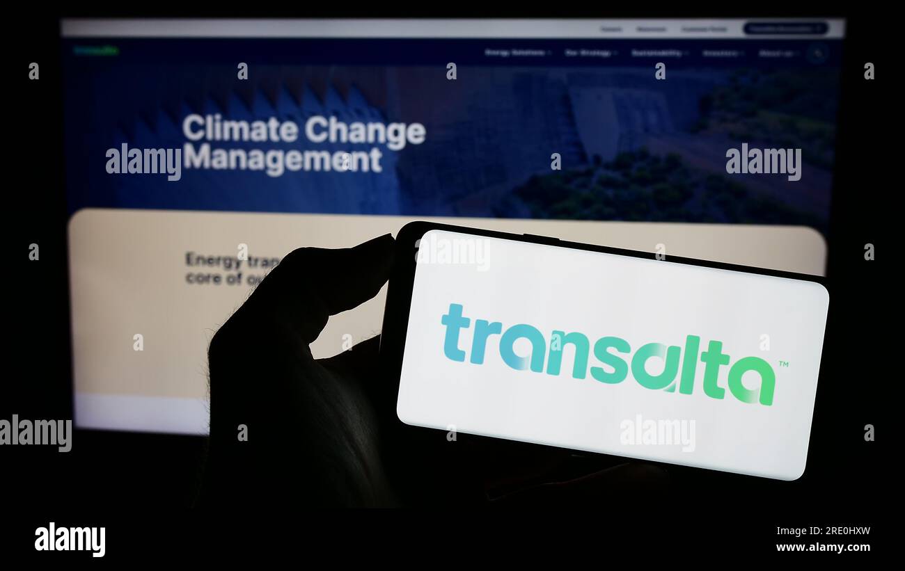 Person holding smartphone with logo of Canadian energy company TransAlta Corporation on screen in front of website. Focus on phone display. Stock Photo