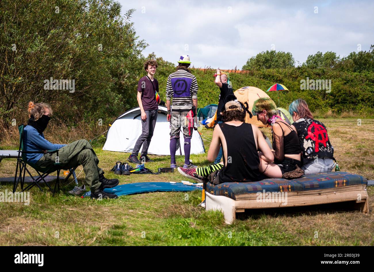 24 July 2023, Schleswig-Holstein, Tinnum/Sylt: Punks sit on the lawn of a  protest camp in Tinnum. Under the motto "Sylt for all", the group "Aktion  Sylt" criticizes a split in society and