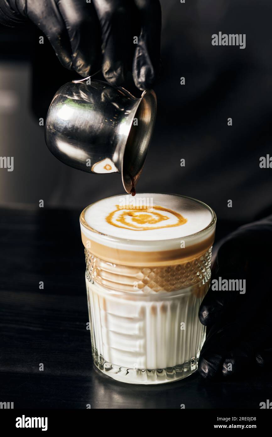 barista preparing latte macchiato, pouring espresso in glass, pitcher with  coffee, milk foam Stock Photo - Alamy