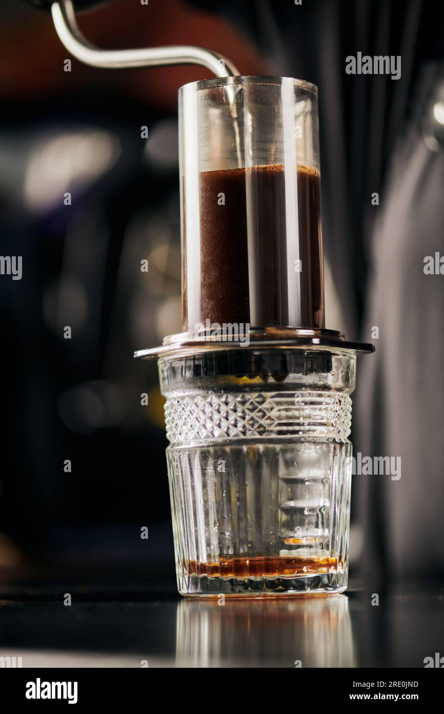 boiling water pouring into aero press coffee maker above crystal glass