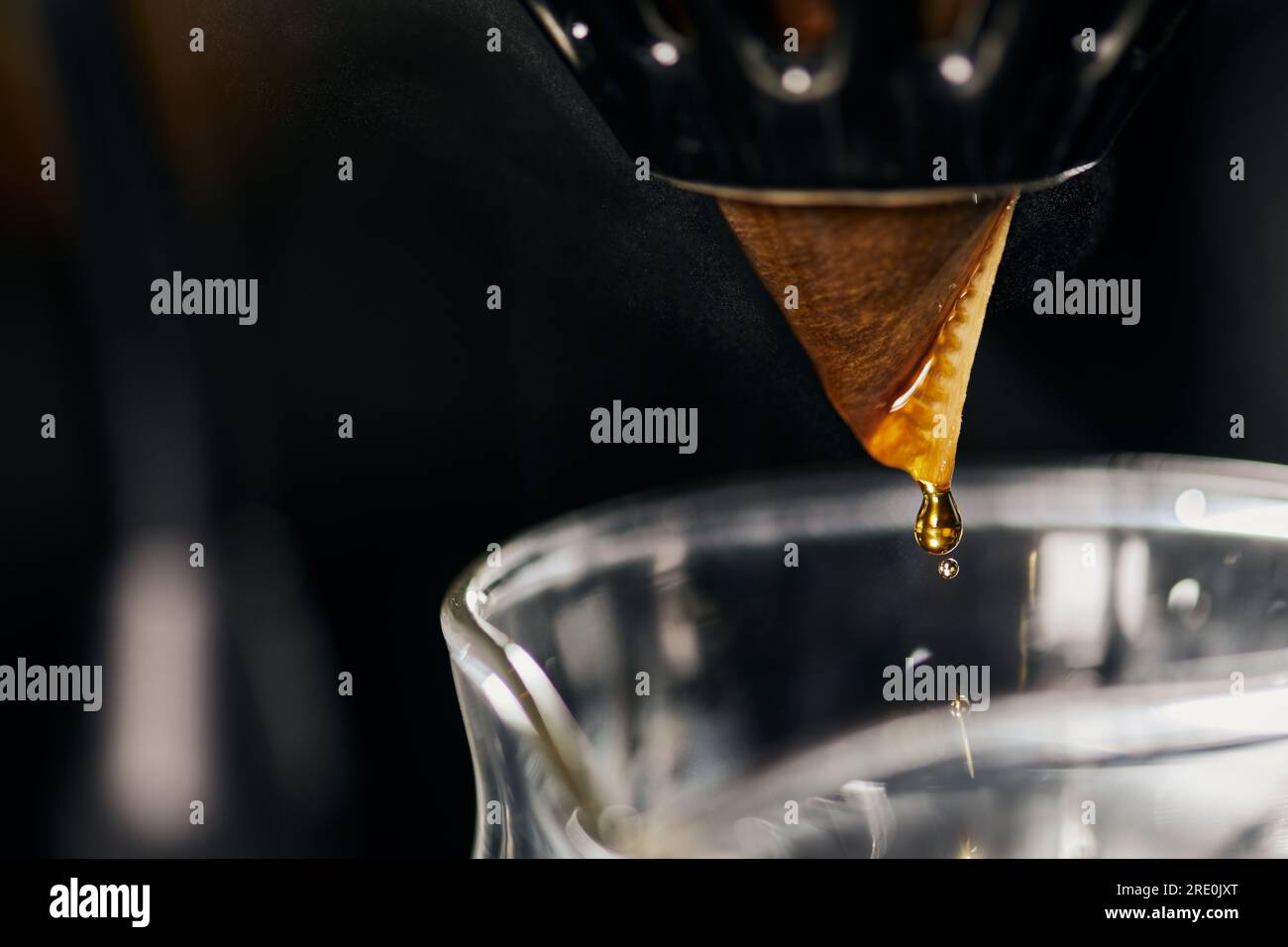 close up view of espresso dripping from paper filter on dripper stand ...