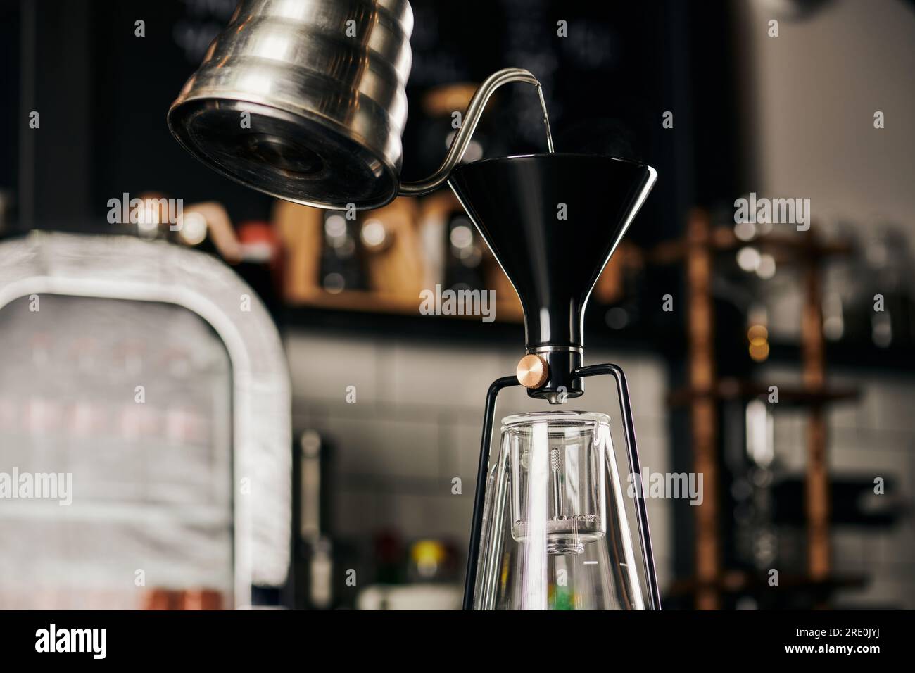 boiling water pouring from drip kettle into siphon coffee maker during