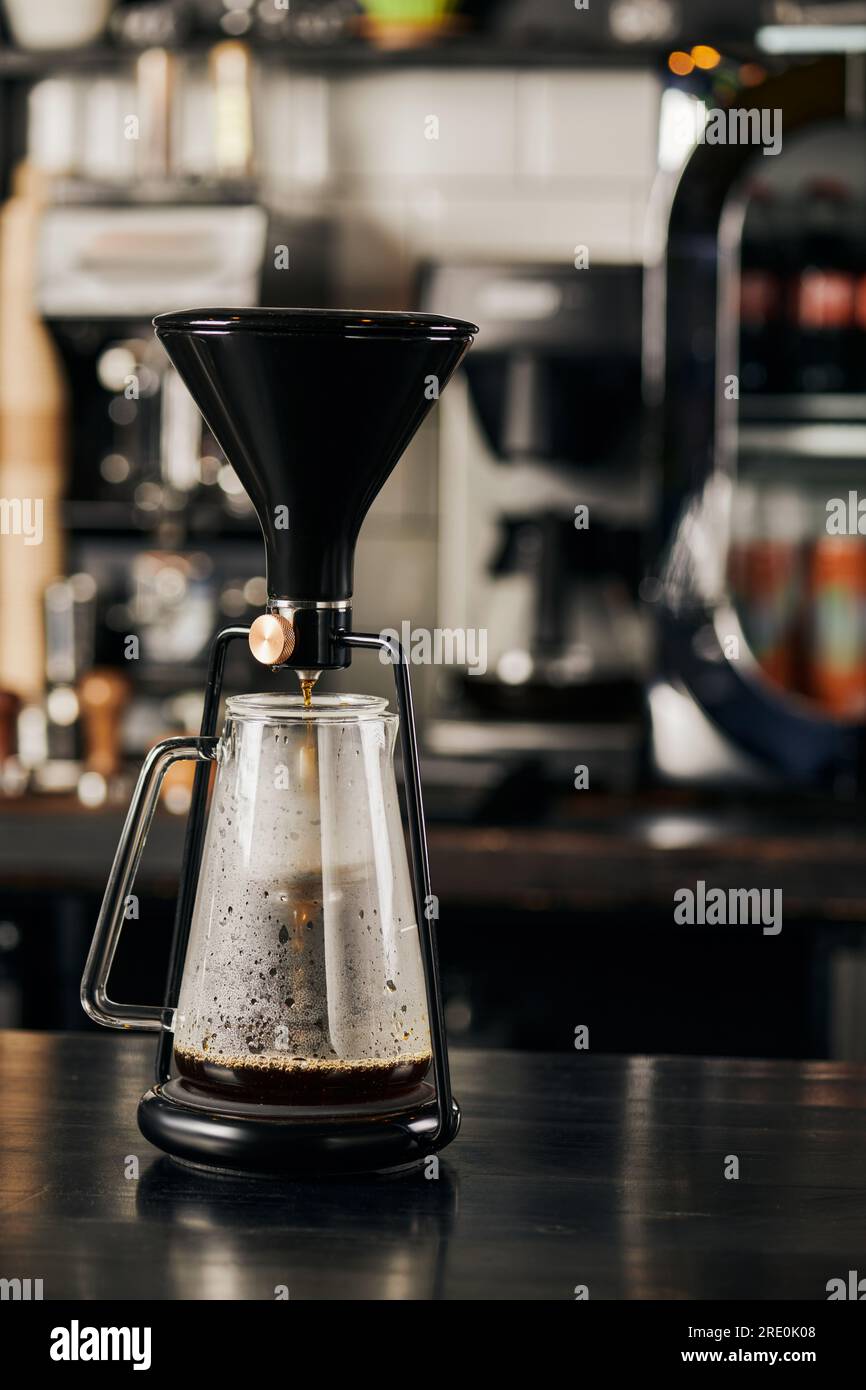 https://c8.alamy.com/comp/2RE0K08/siphon-coffee-maker-with-fresh-espresso-in-glass-coffee-pot-on-black-wooden-table-in-modern-cafe-2RE0K08.jpg