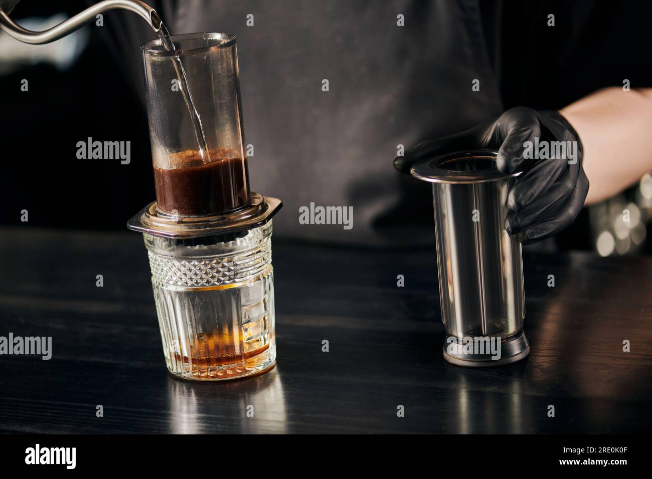 partial view of barista pouring boiling water in aero press coffee
