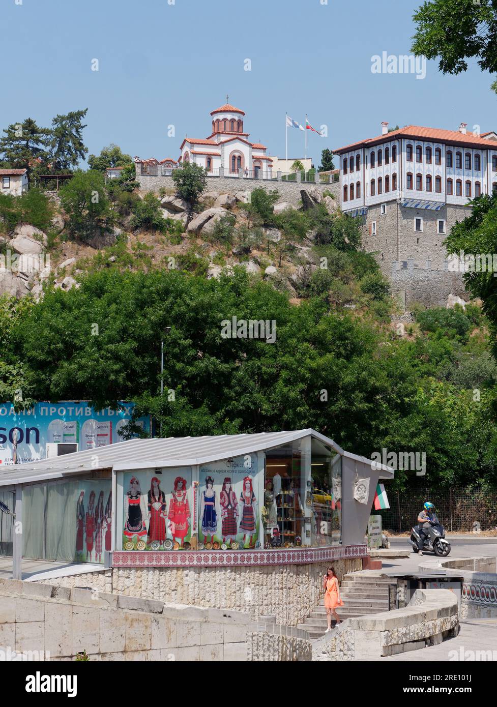 Plovdiv, Bulgaria. Subway entrance area and shop with illustrations f traditional clothing. Church in background on the hill. Stock Photo