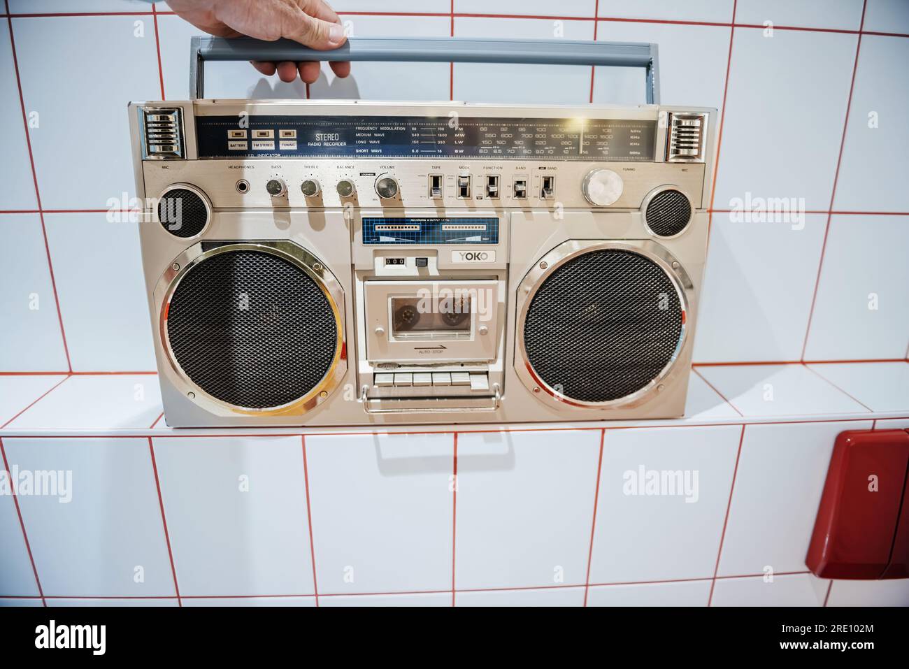 Schiltach, Germany - Jul 14, 2022: Silver 80s urban retro radio, portable boombox with cassette tape player and bright buttons - man hand on top. Vintage digital technology for nostalgic projects Stock Photo