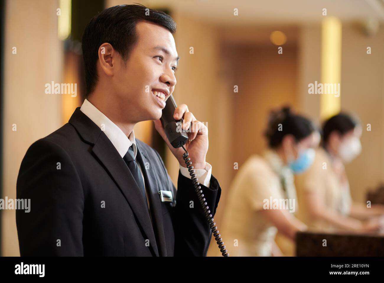 Vietnamese spa hotel manager talking on phone with guest ordering