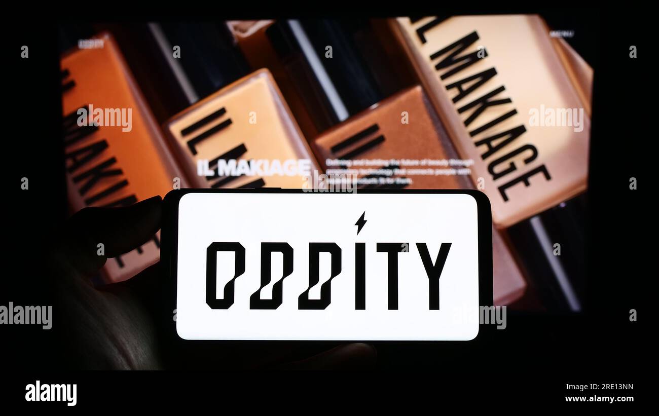 Person holding cellphone with logo of US consumer technology company Oddity Inc. on screen in front of business webpage. Focus on phone display. Stock Photo