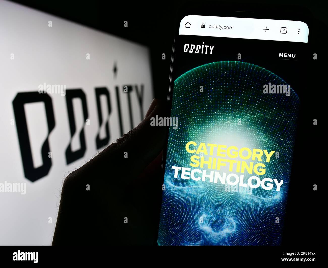 Person holding cellphone with website of US consumer technology company Oddity Inc. on screen in front of logo. Focus on center of phone display. Stock Photo