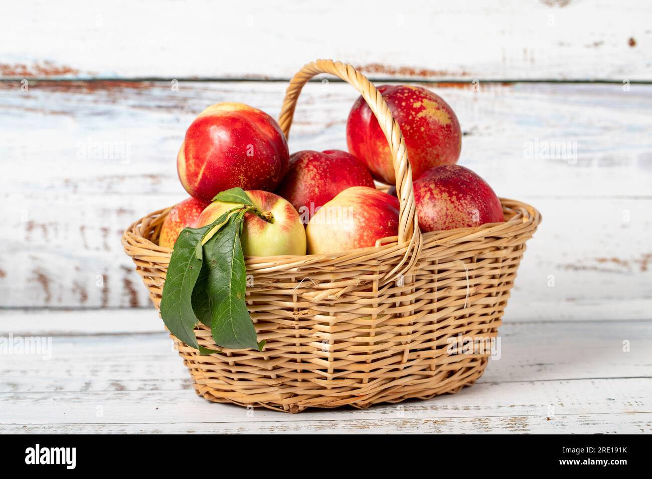 Fresh nectarine in a wicker basket over wooden background. Nectarine harvest season concept. Healthy and fresh fruit Stock Photo