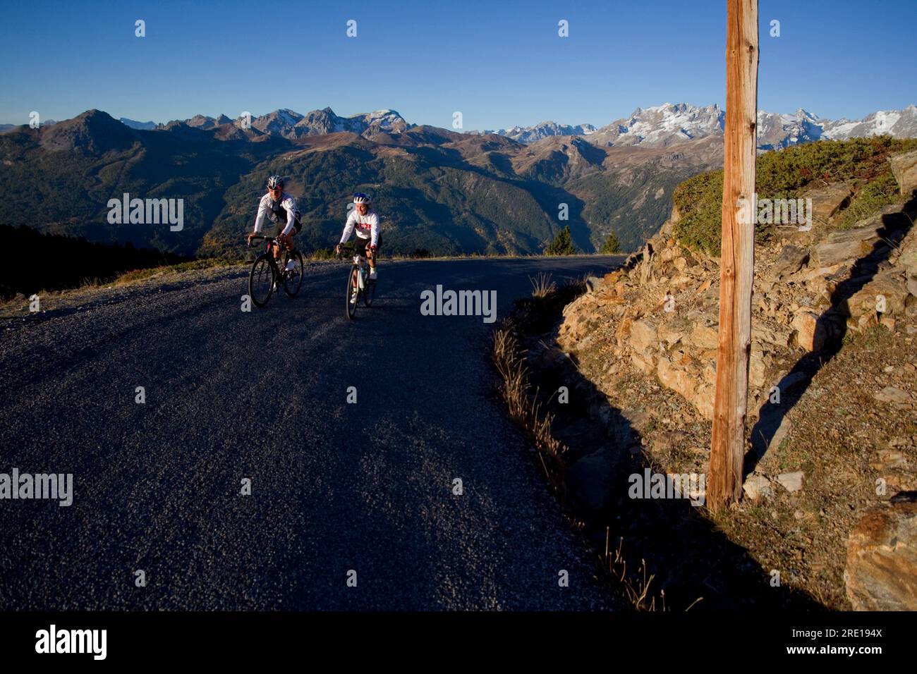 Two cyclists climbing the legendary Col (Granon Pass) in autumn, in the French Alps. Couple of cyclists on a mountain road with a panoramic view of th Stock Photo