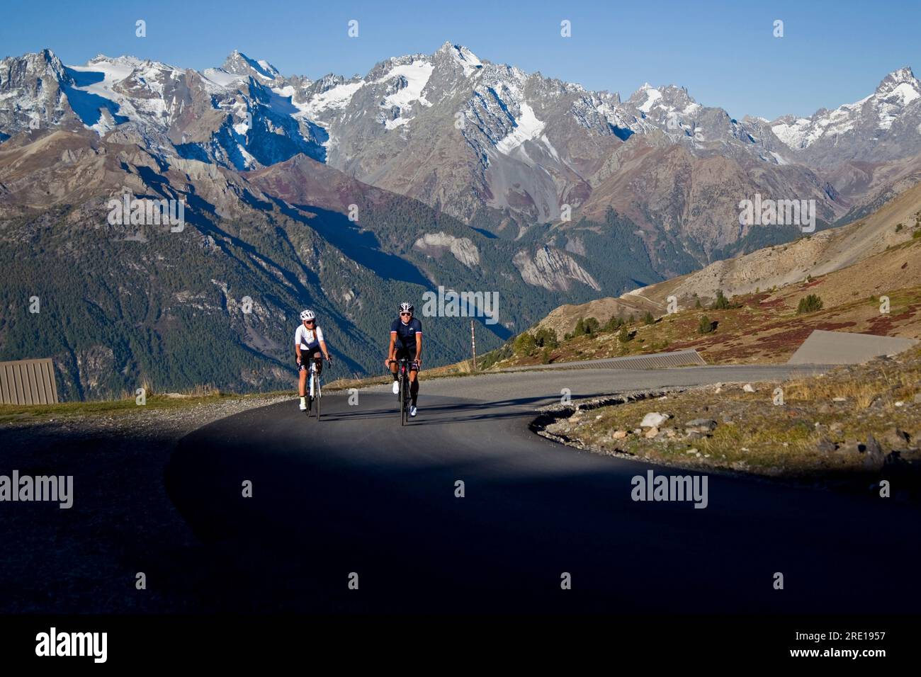 Two cyclists climbing the legendary Col (Granon Pass) in autumn, in the French Alps. Couple of cyclists on a mountain road with a panoramic view of th Stock Photo