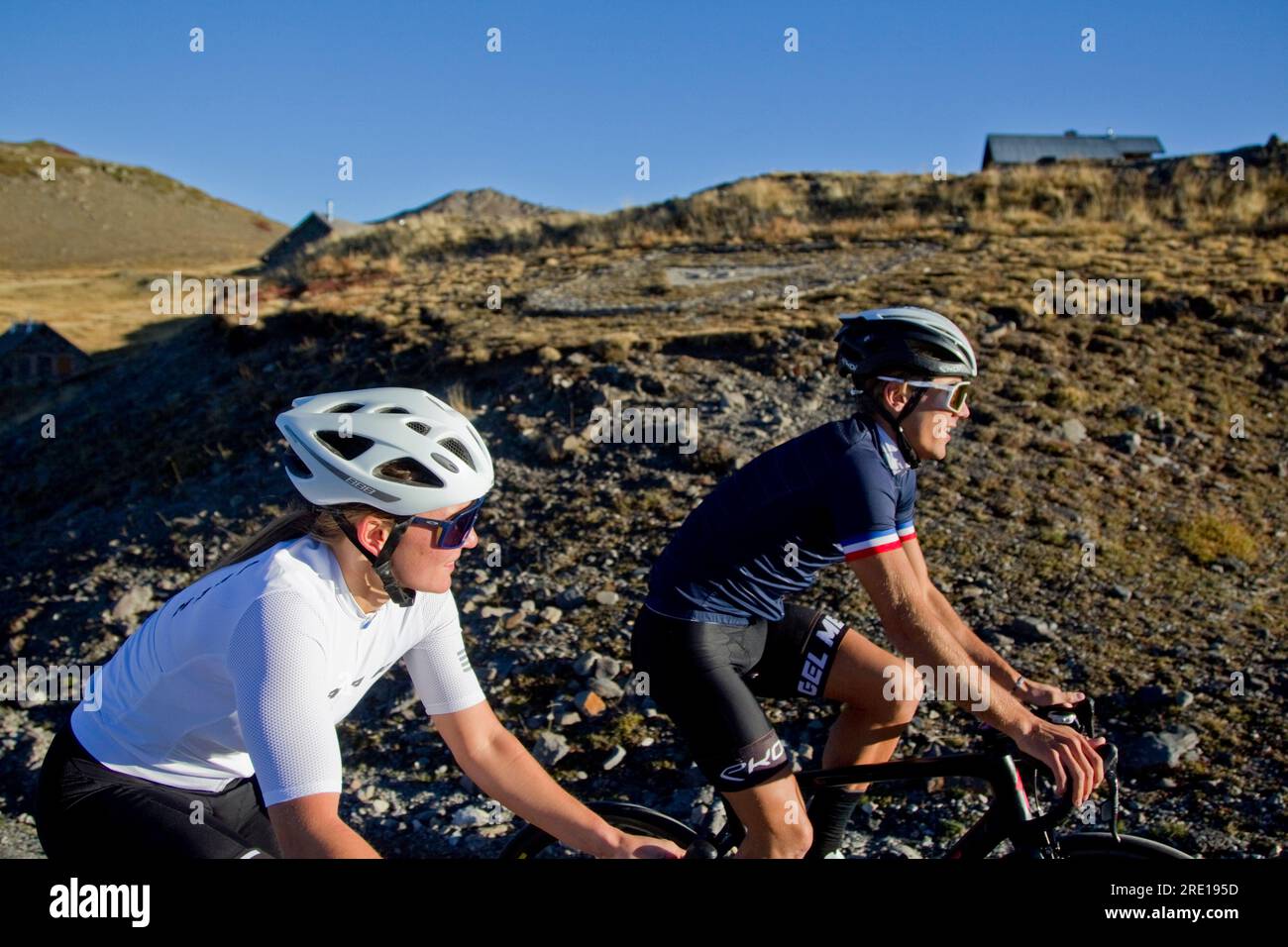 Two cyclists climbing the legendary Col (Granon Pass) in autumn, in the French Alps. Couple of cyclists on a mountain road. Stock Photo