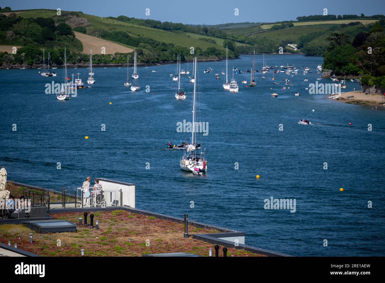 View along Salcombe estuary with yachts at anchor and the Harbour Hotel in the foreground on a bright summers day with calm water Stock Photo