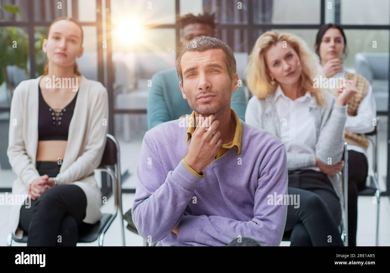 Businessman sitting in front of his colleagues looking at the camera Stock Photo