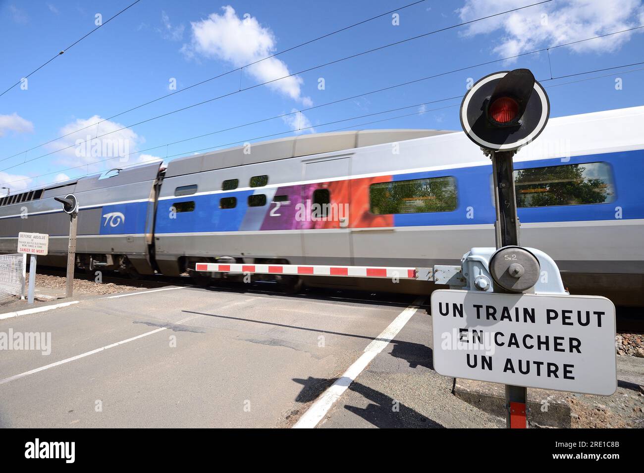 Level crossing on a country road with automatic railway gate. Automatic gates lowered, gates closed, red light flashing and TGV high speed train passi Stock Photo