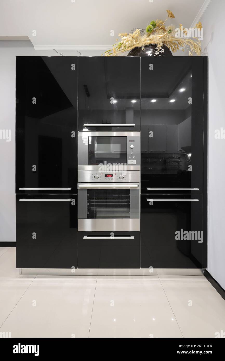 Glossy black kitchen furniture with built-in microwave and electric oven Stock Photo