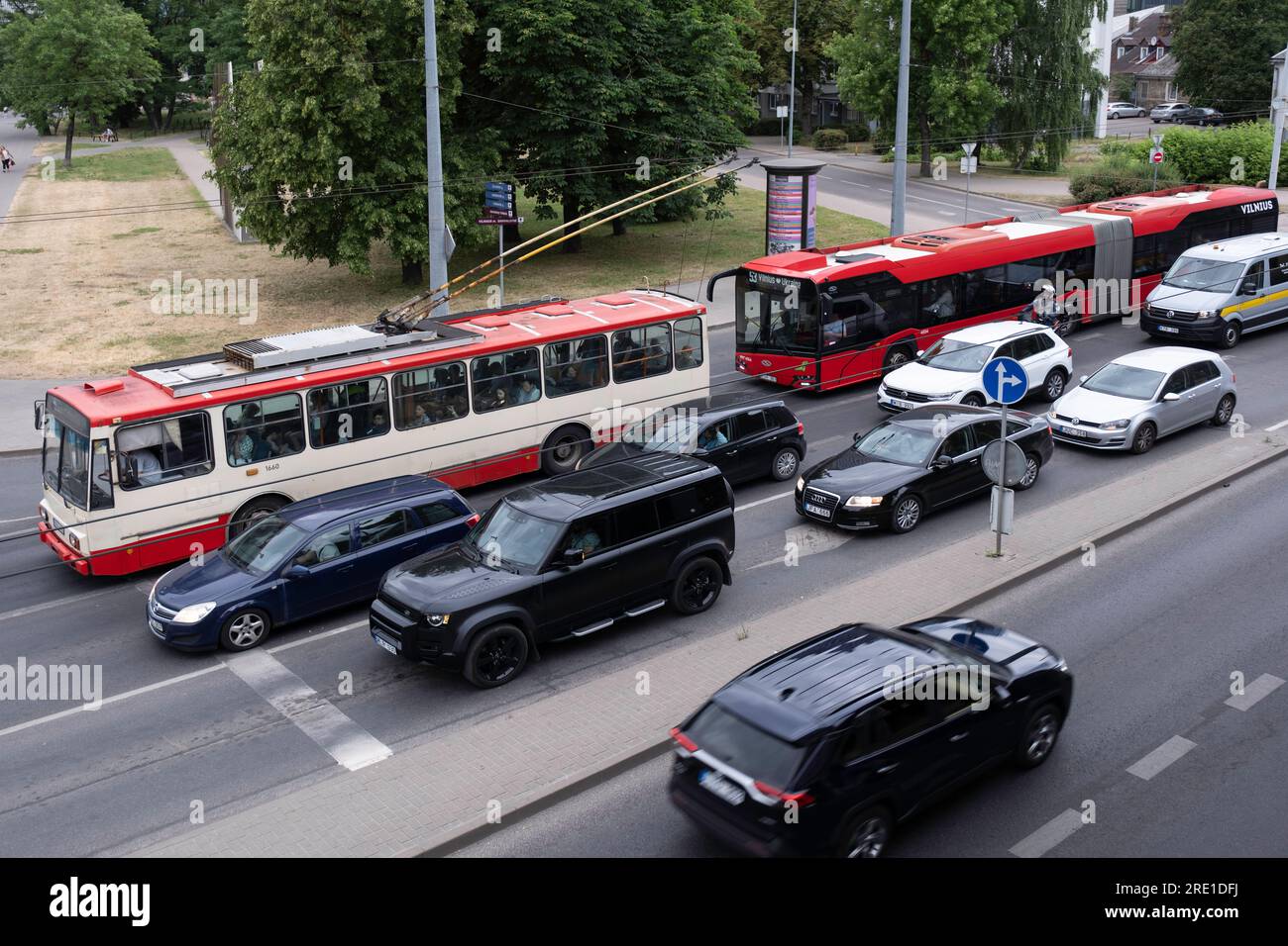 Old and new Skoda Trolley Bus and cars are waiting in front of the traffic light in Vilnius. Public transport VVT (Vilniaus viešasis transportas) Stock Photo