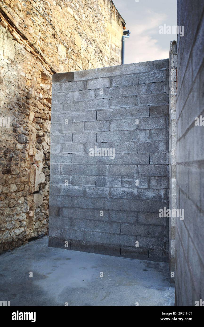 Cinder block wall against an old stone wall Stock Photo
