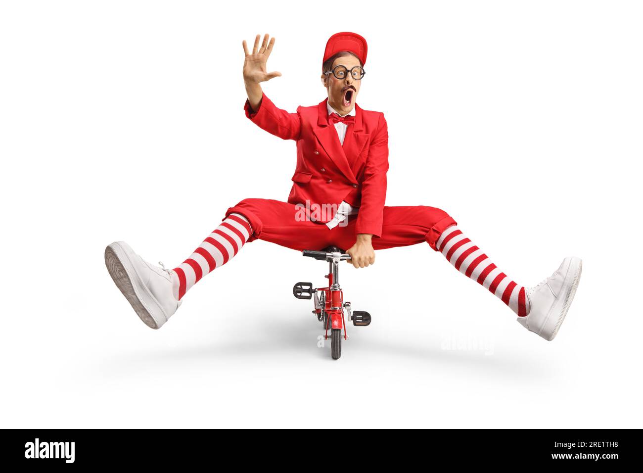 Entertainer in a red suit riding a small bike and waving isolated on white background Stock Photo