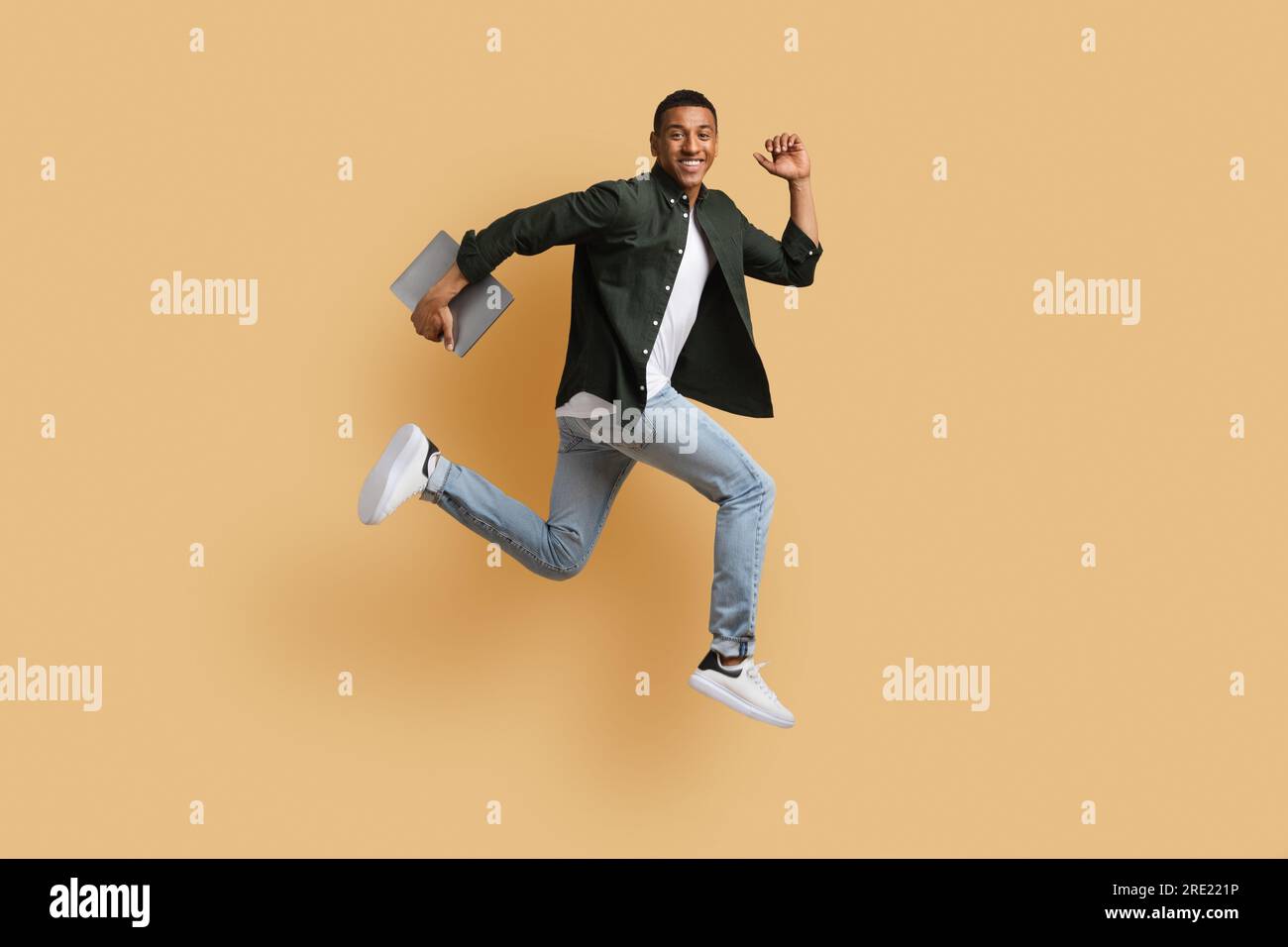 Excited young black guy independent contractor running with computer Stock Photo