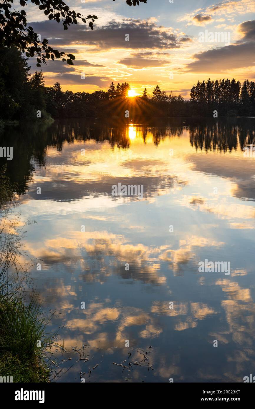 A lake (Postfeldener Stausee) in Bavaria in the nature reserve Höllbachtal at sunset with the sky reflecting in the lake. Germany. Stock Photo