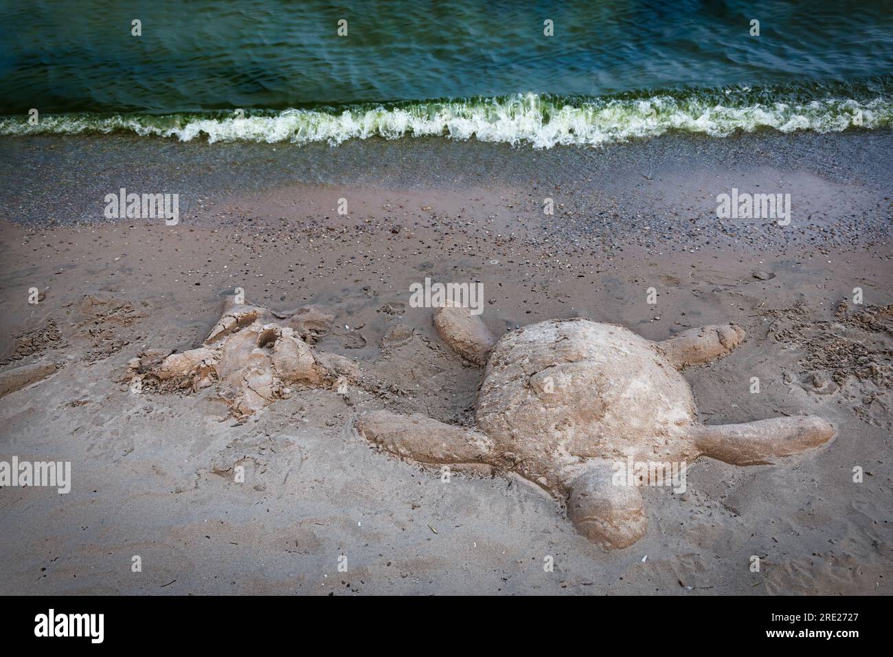 A sand sculpture of a turtle and sea star, left by visitors to a sand sculpting festival, begins to wash away on shores of Lake Michigan at Manitowoc, Stock Photo