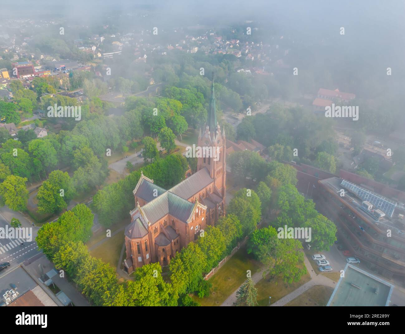 Gothic style Palanga church in haze, Lithuania. Aerial view on a foggy day. Low clouds over the city Stock Photo