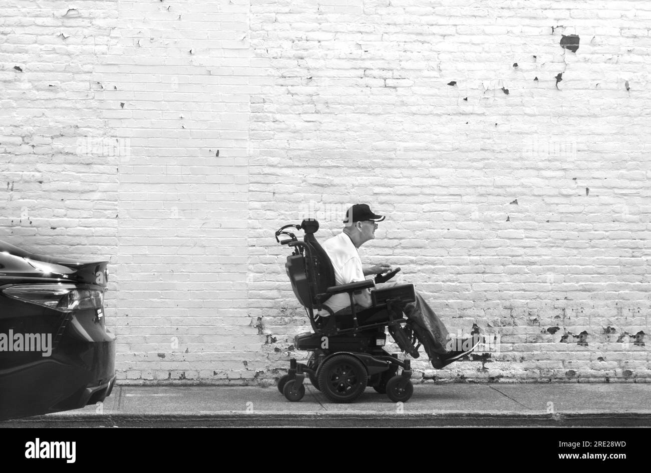 A man rides a battery-powered electric power chair or wheelchair along a sidewalk in Bristol, Virginia. Stock Photo