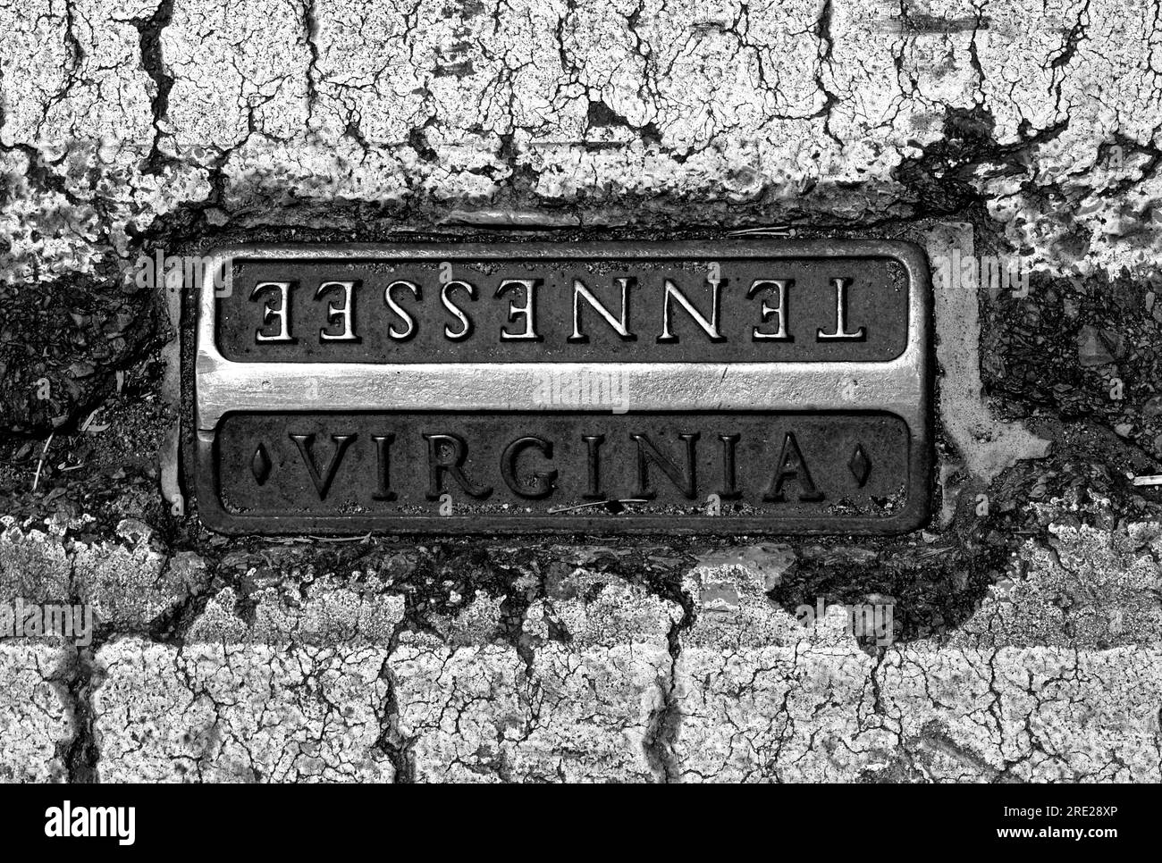 A metal marker in the middle of State Street in downtown Bristol, Virginia and Bristol, Tennessee. The street is the dividing line between the states. Stock Photo