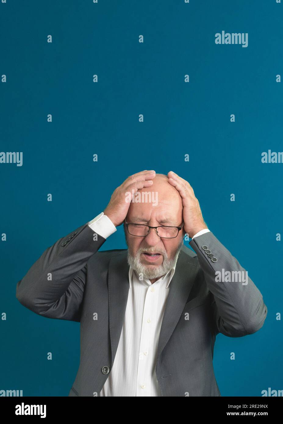 Senior man has a headache. hands on forehead - Need for medical and healthcare help. blue background Stock Photo