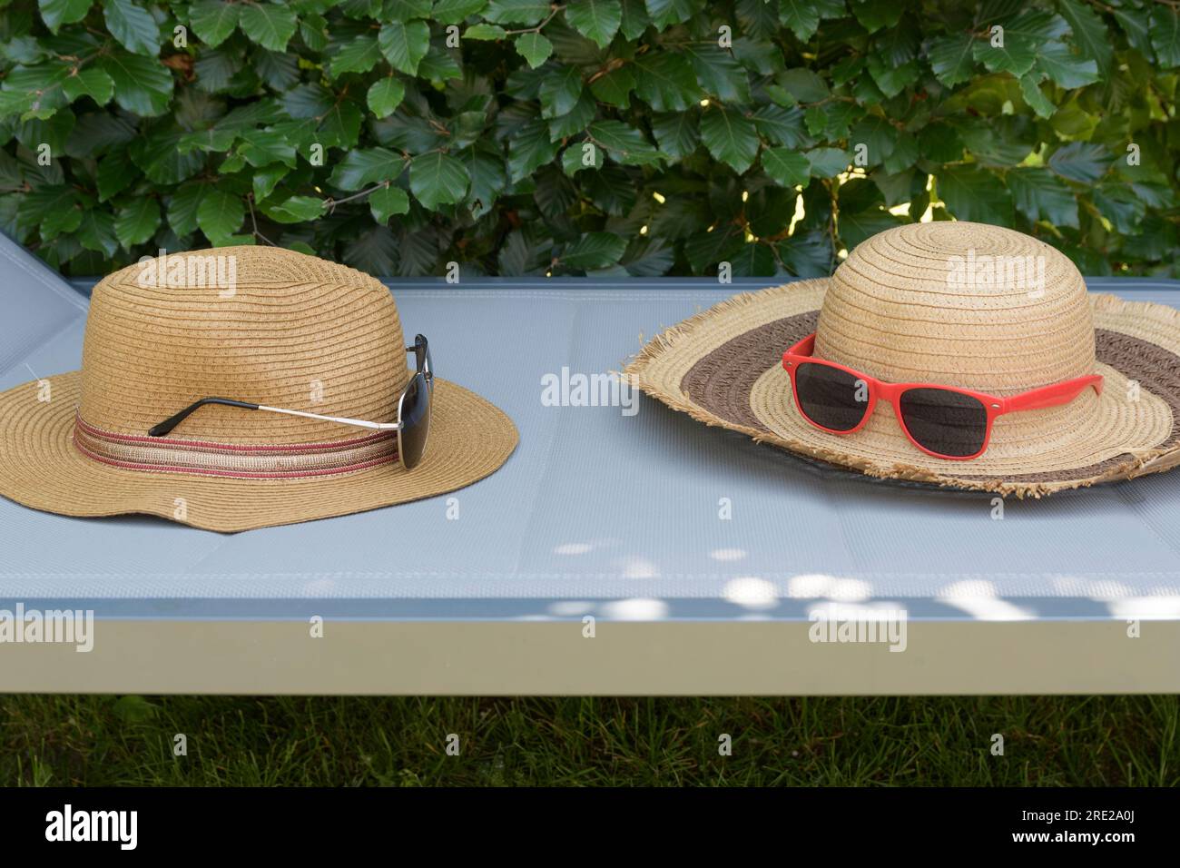 A beach lounger with sunglasses and straw hats for women and men. Still ...