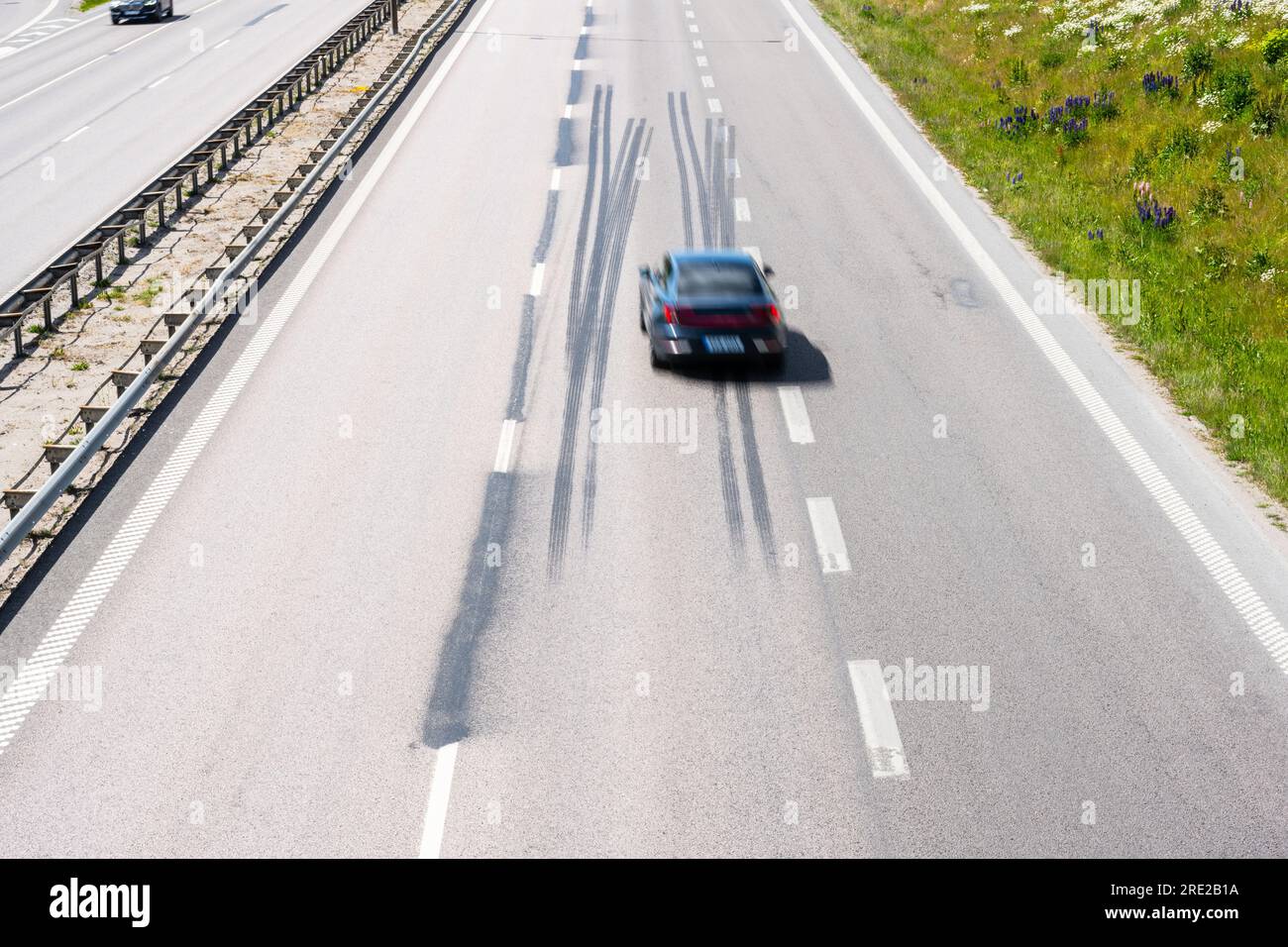 Car driving fast down a highway with log tire skid marks Stock Photo