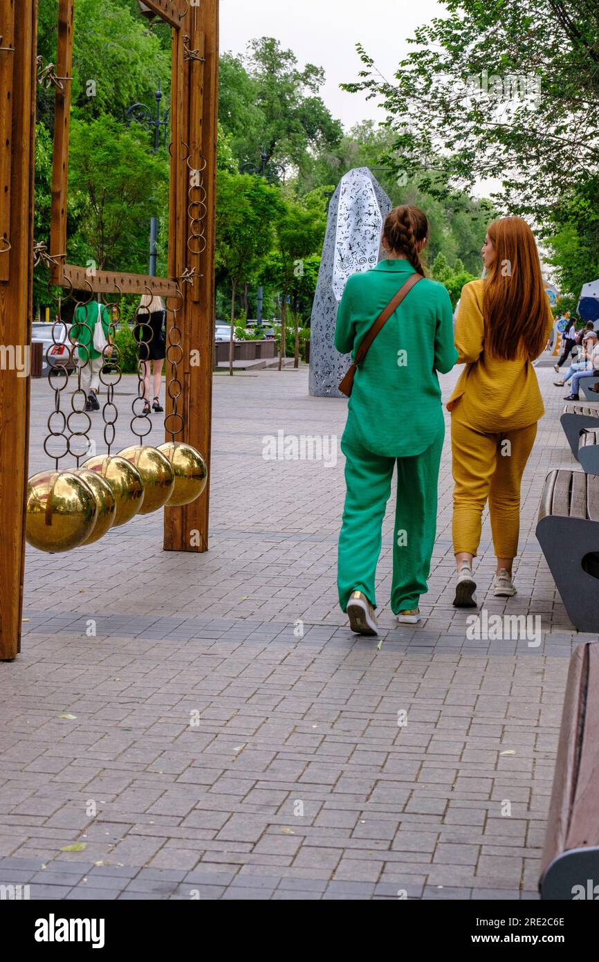 Kazakhstan, Almaty. Women Walking Past an Artistic Decoration on the Panfilov Promenade, a Pedestrian Walkway. Stock Photo