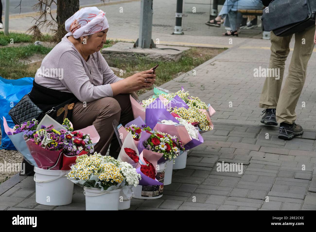 Kazakhstan, Almaty. Street Scene: Woman Selling Flowers. Stock Photo