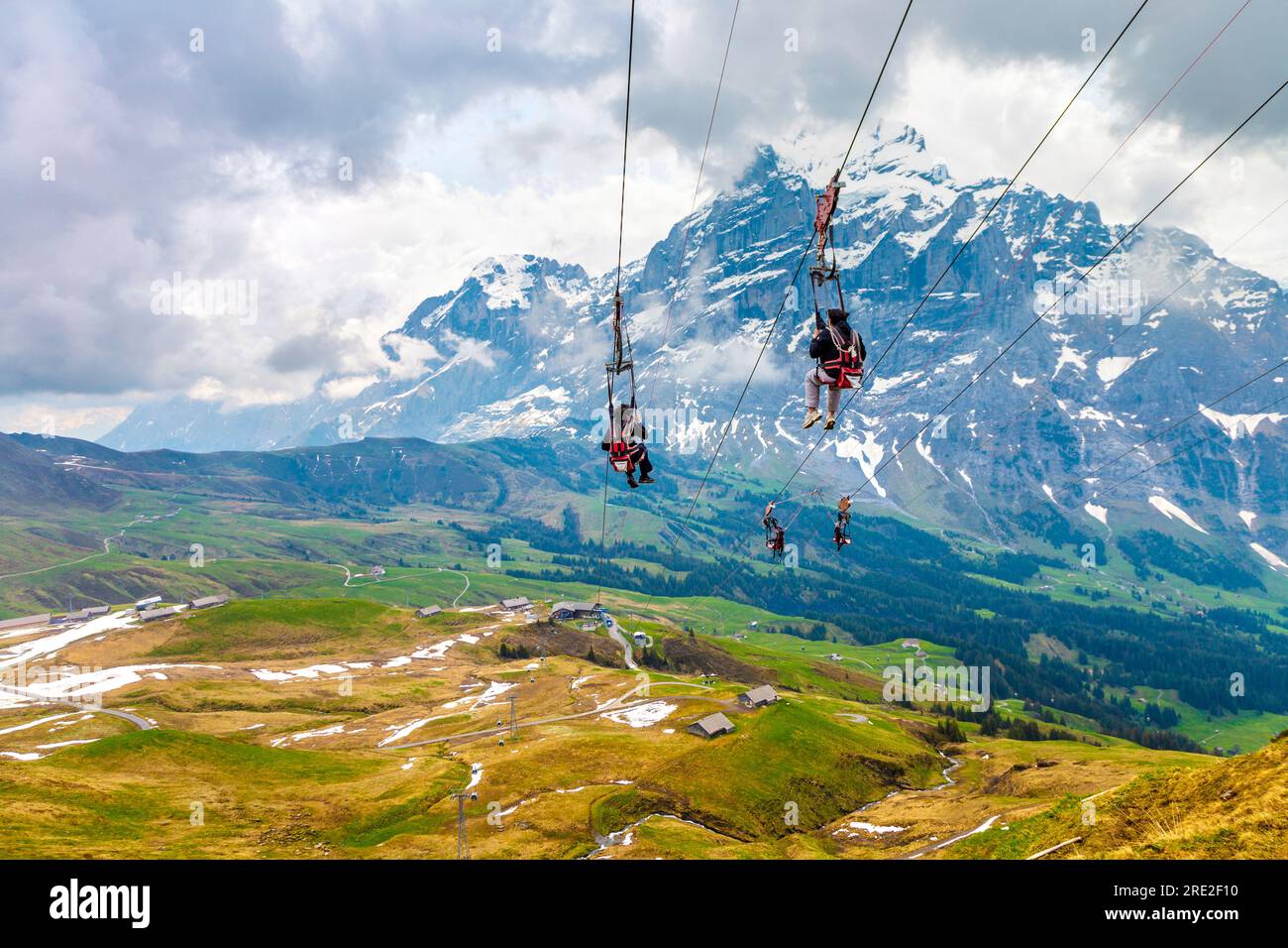 People on the First Flyer zip line at the summit of First mountain, Wetterhorn in background, Switzerland Stock Photo