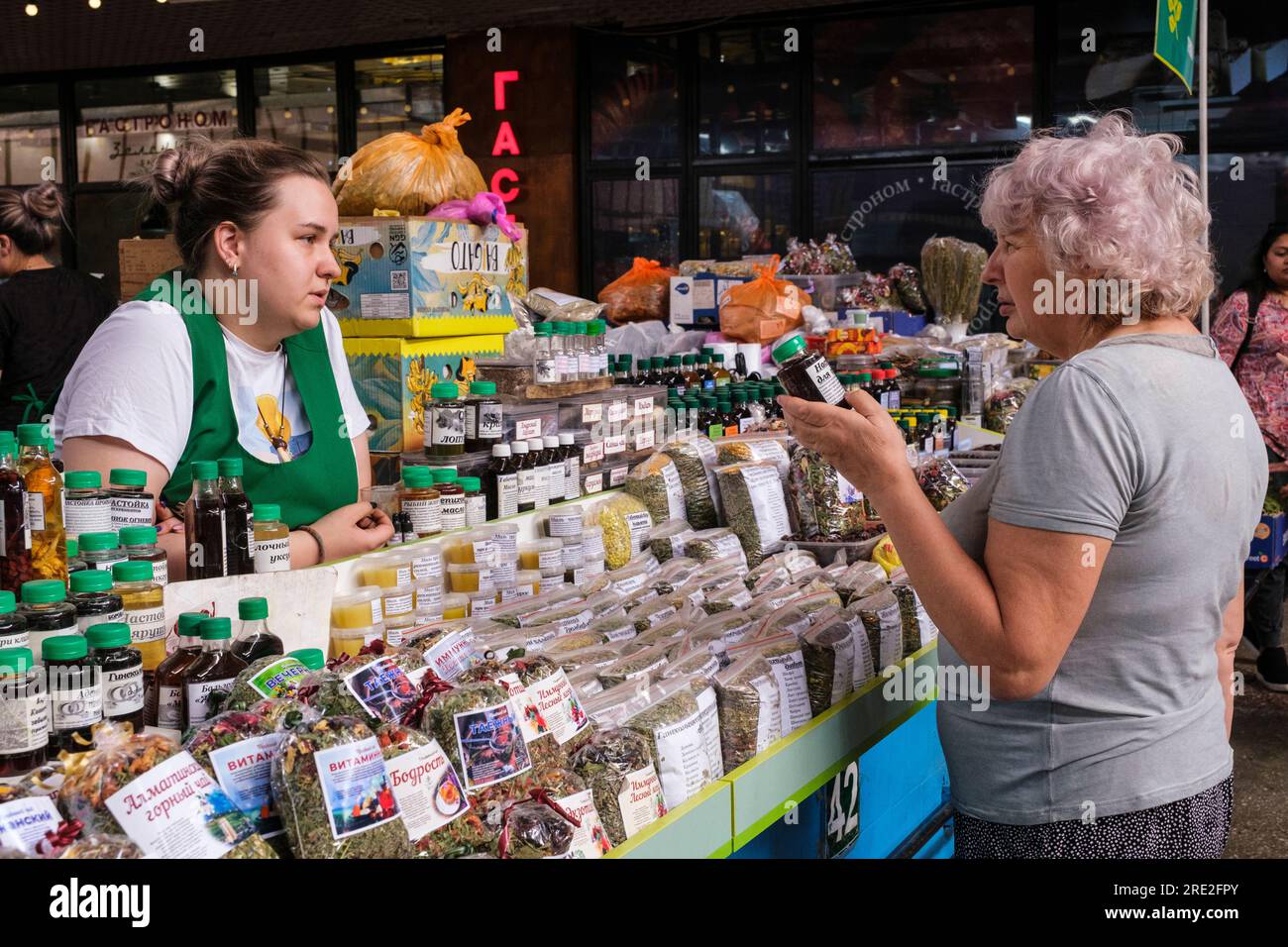 Kazakhstan, Almaty. Green Bazaar Vendor of Health Care Supplements and Herbal Teas Talking to a Customer. Stock Photo