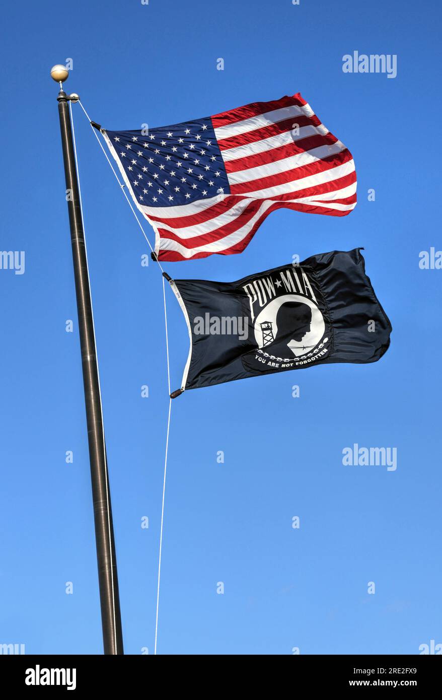 Willard, Missouri - February 21, 2016: The American Flag with the POW MIA Flag flying against a blue sky.  The POW MIA flag is a symbol of US military Stock Photo