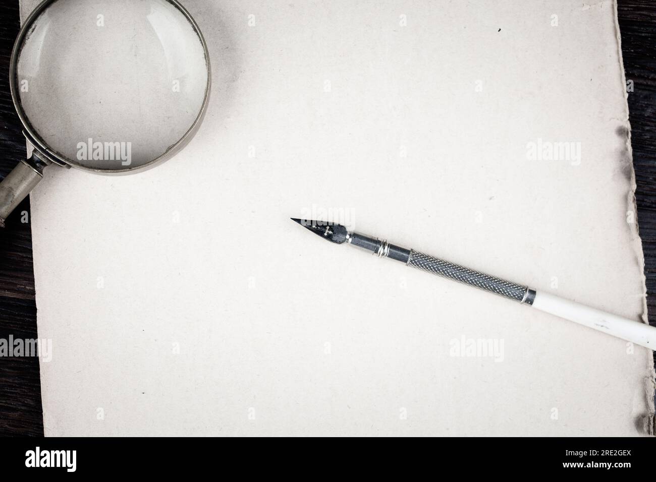 Magnifying glass with old ink feather pen on paper background Stock ...