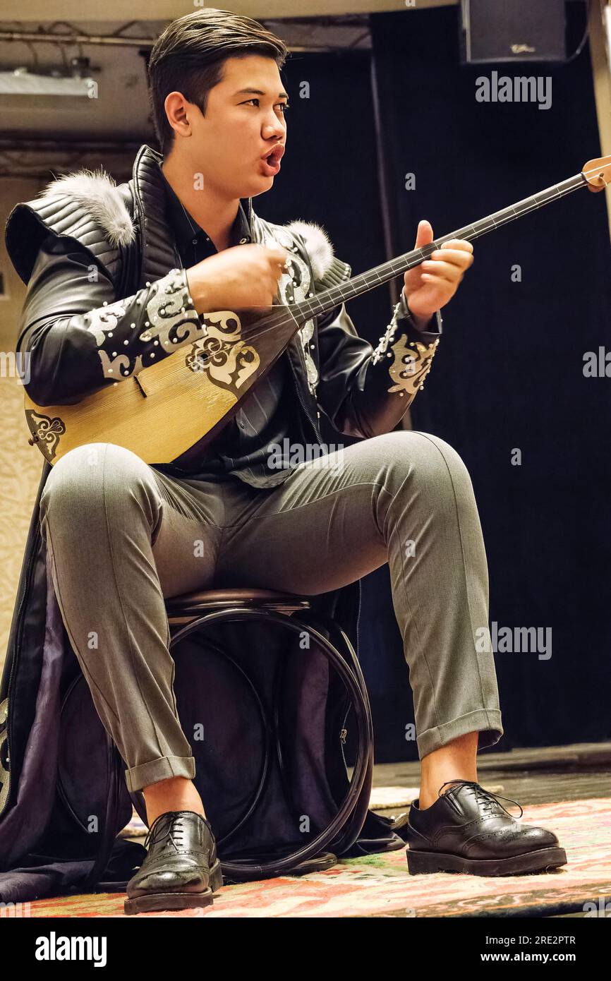Kazakhstan, Almaty. Young Musician Playing the Dombra, a Traditional Kazakh Stringed Instrument found among the Turkic Peoples of Central Asia. Stock Photo