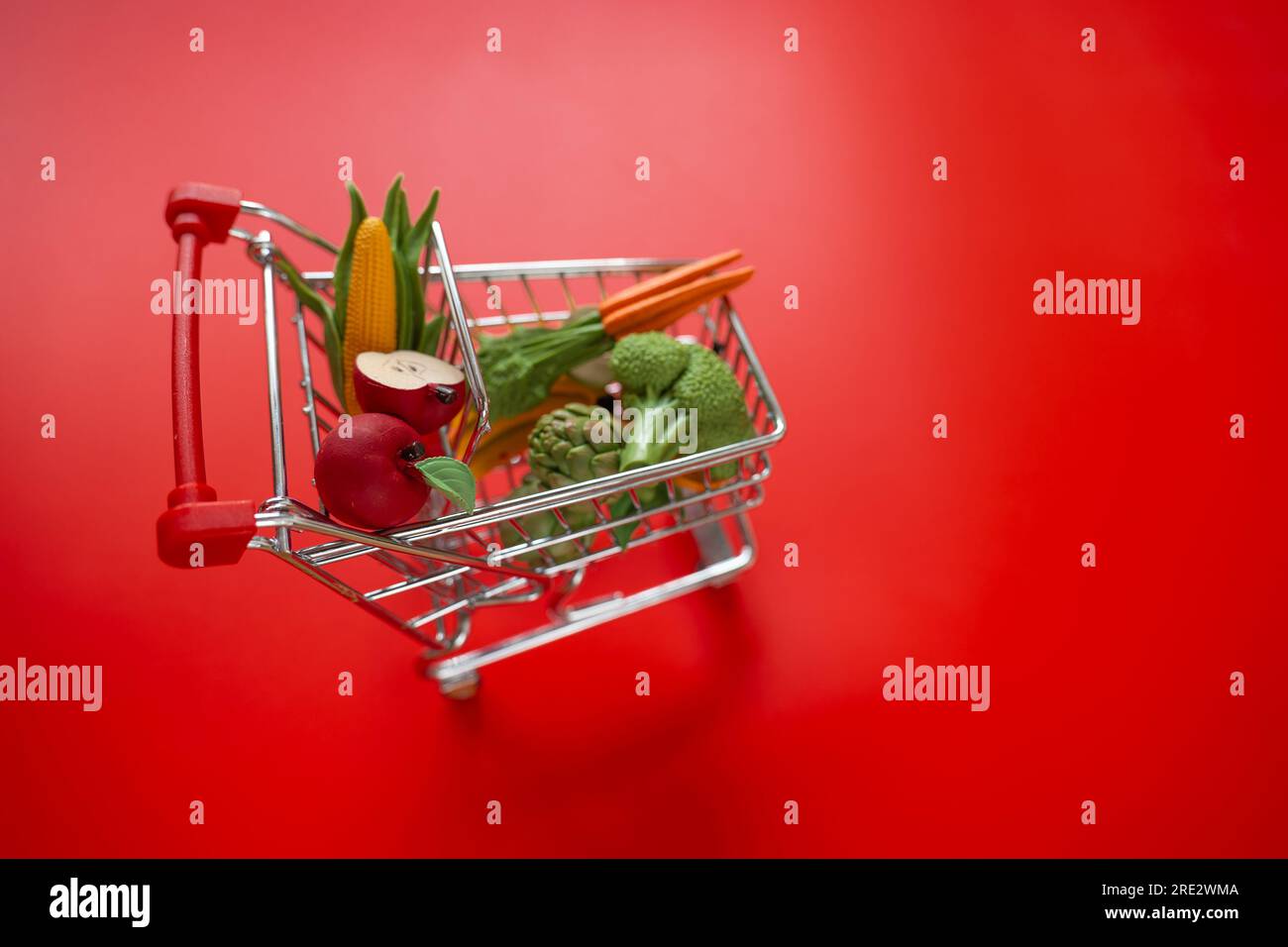 Shopping cart with groceries on a red background.grocery consumer