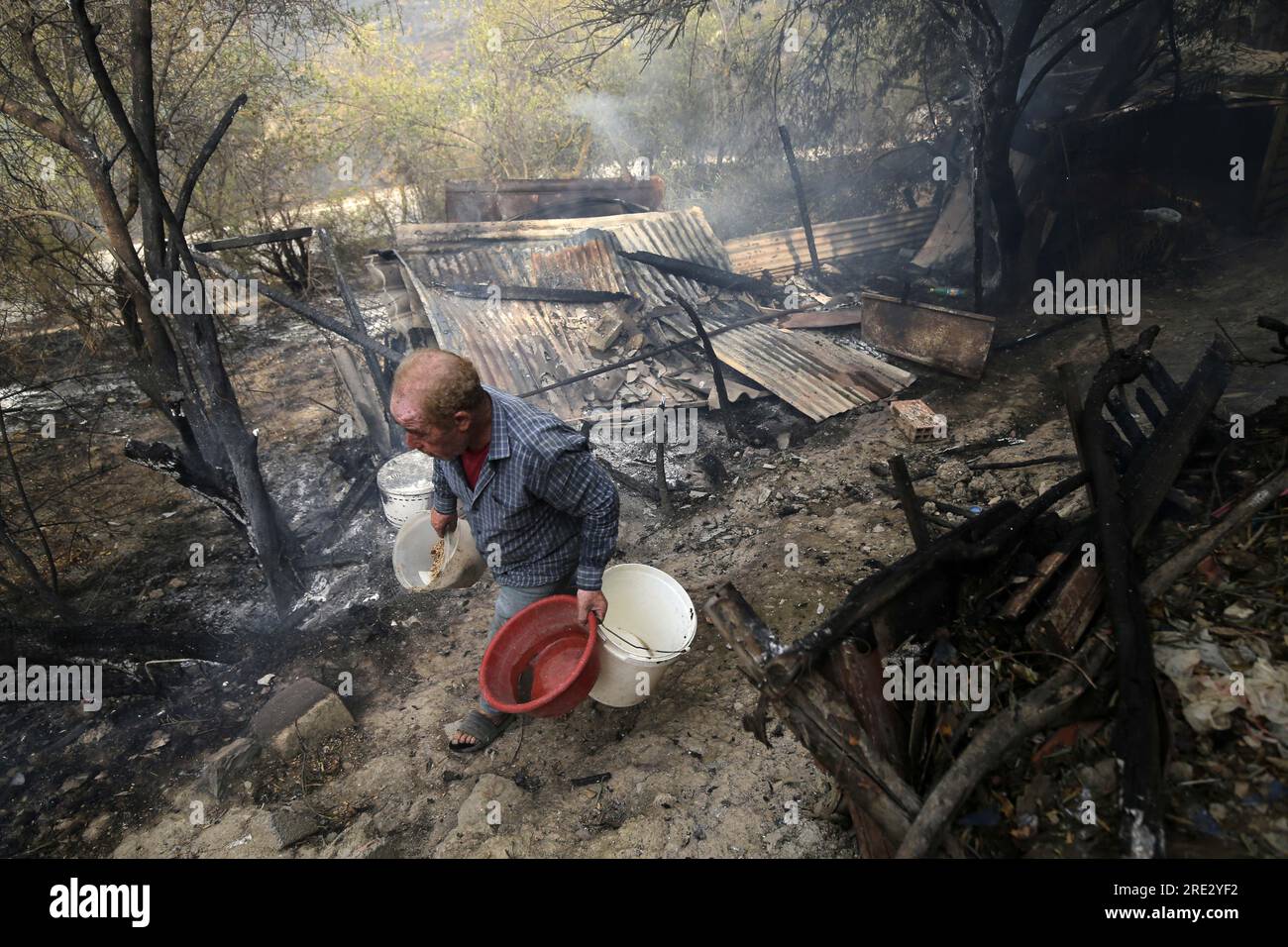 (230724) -- BOUIRA (ALGERIA), July 24, 2023 (Xinhua) -- A man walks past a house burned down in a wildfire in Bouira Province, Algeria, on July 24, 2023. The death toll from wildfires in northern Algeria has risen to 34, including 10 soldiers, the Interior Ministry said in an update on Monday. (Xinhua) Stock Photo