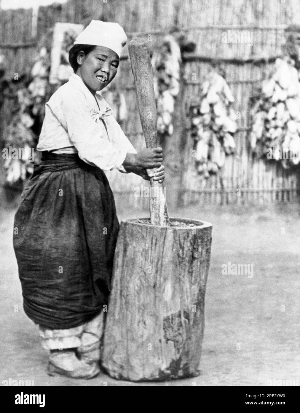 Korea c. 1940 A Korean girl is mashing cooked soybeans with a wooden