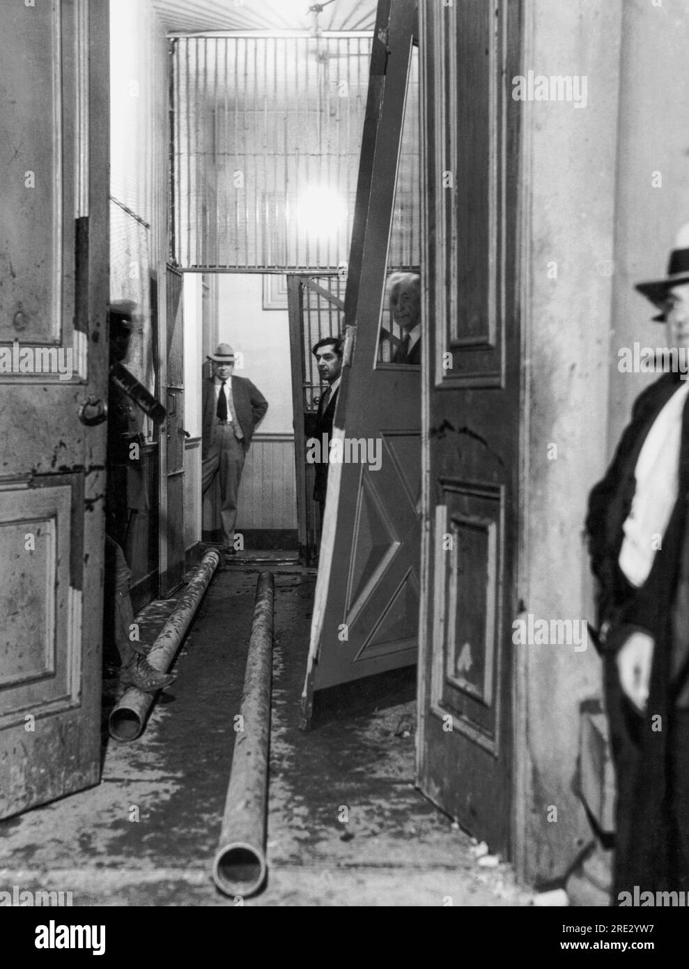 San Jose, California:   November 27, 1933. Police officers look at the 30 foot lengths of pipe that the lynch mob used as battering rams to break down the two iron doors of the jail. The officers' efforts to save the kidnapers, John Holmes and Thomas Thurmond, from the mob were futile. Stock Photo
