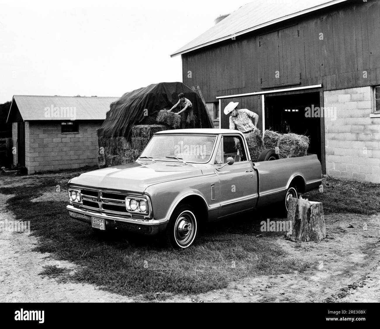 United States   1967 A farmer loading bales of hay into his new GMC light duty pickup truck. Stock Photo