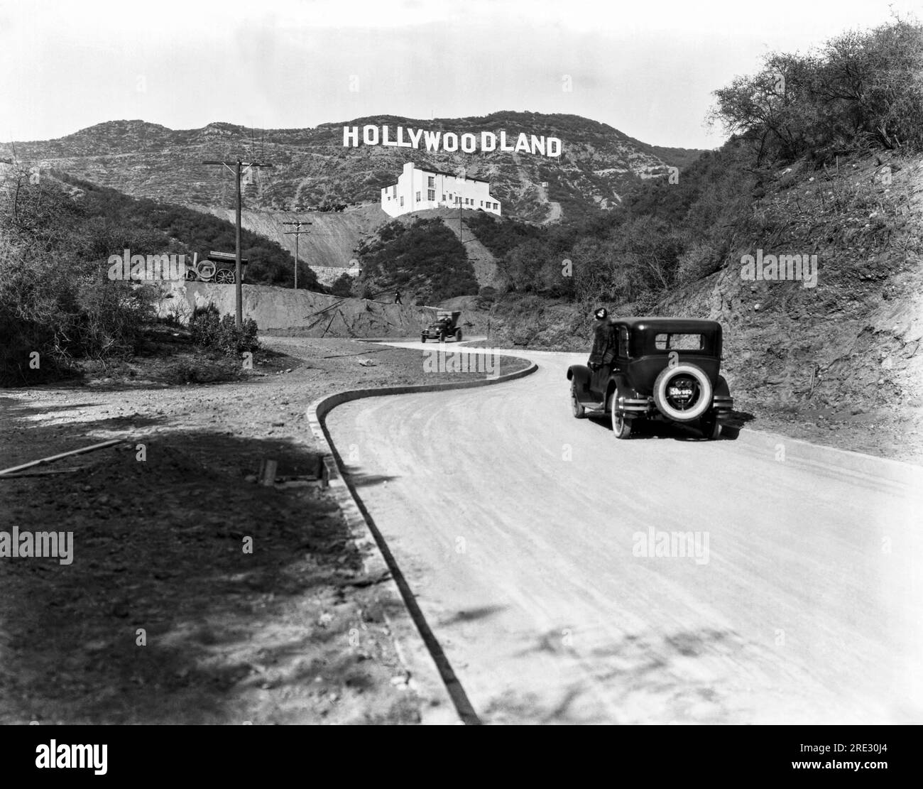 Hollywood, Los Angeles:  c. 1924 A sign advertises the opening of the Hollywoodland housing development in the hills on Mulholland Drive overlooking Los Angeles. The white building below the sign is the Kanst Art Gallery, which opened on April 1, 1924 Stock Photo