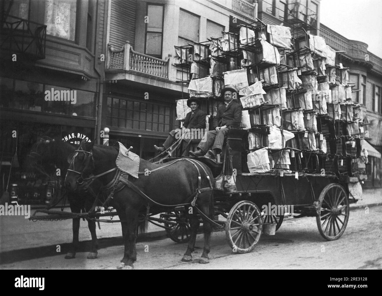 United States:  c.  1900 Two men with a wagon piled high with new chairs. Stock Photo