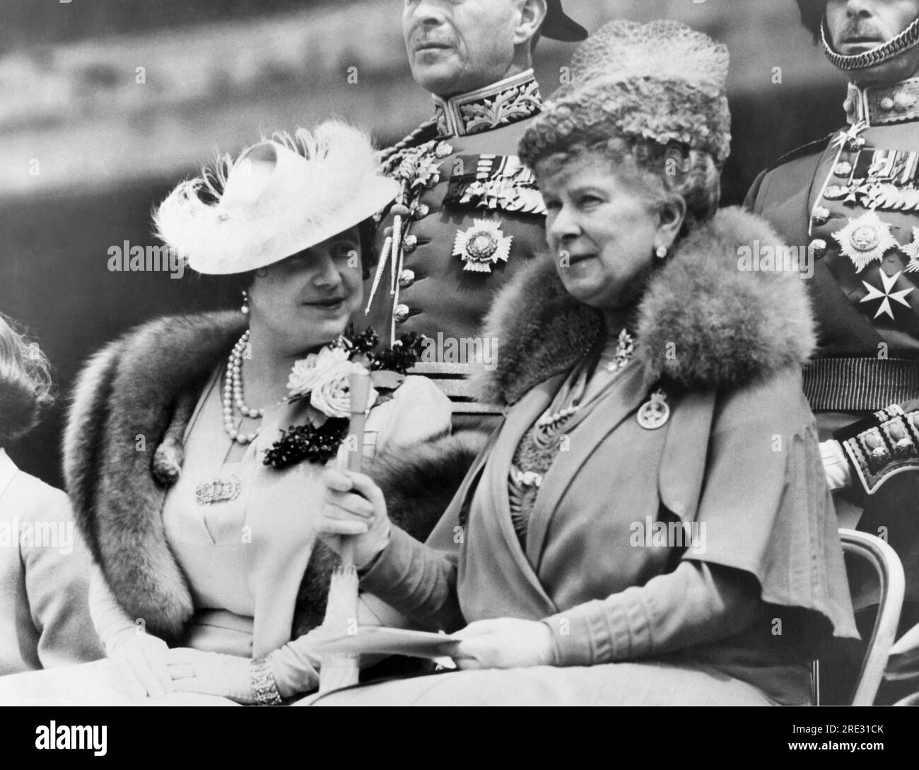 London, England:    May 30, 1938 Queen Elizabeth (L), and Queen Mary chatting as they watched King George present new colors to the 2nd Battalion Grenadier Guards on the grounds of Buckingham Palace. Stock Photo