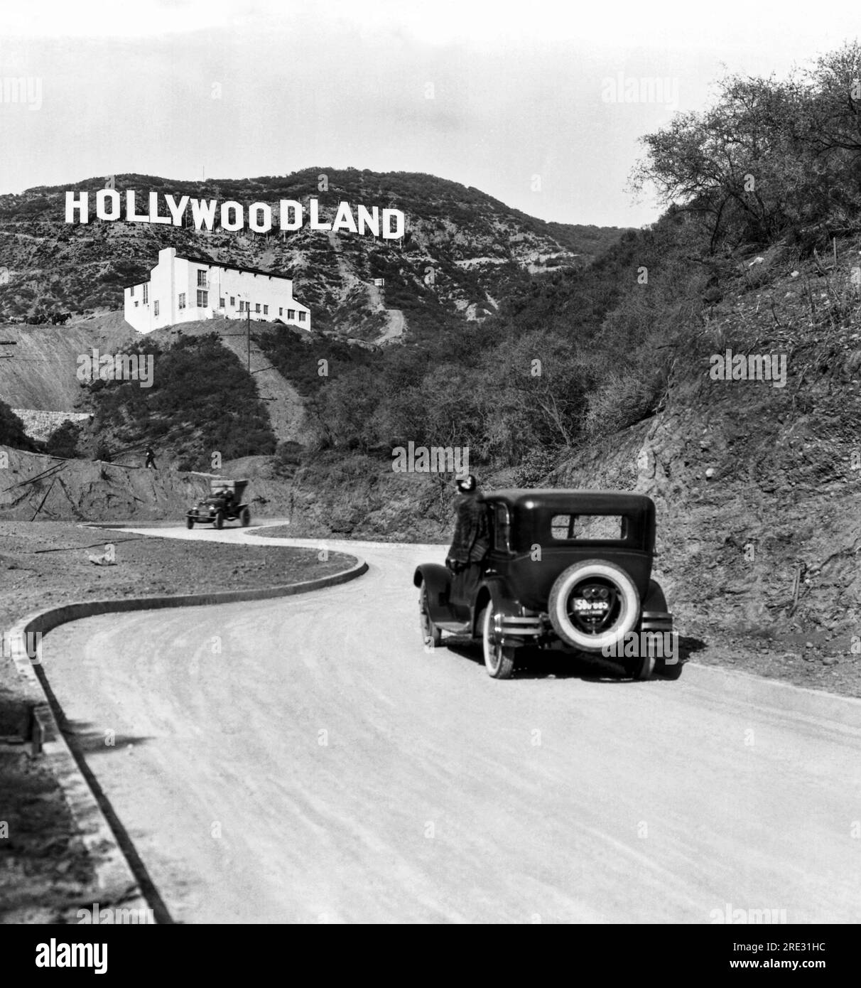 Hollywood, Los Angeles:  c. 1924 A sign advertises the opening of the Hollywoodland housing development in the hills on Mulholland Drive overlooking Los Angeles. The white building below the sign is the Kanst Art Gallery, which opened on April 1, 1924 Stock Photo